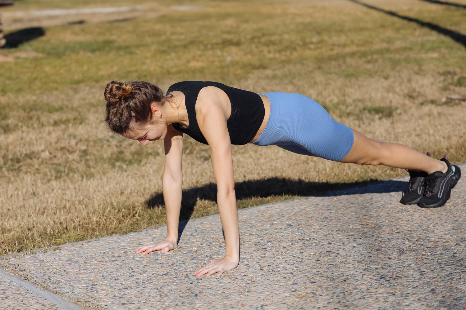 Una mujer con ropa de deporte hace una flexión de brazos al aire libre