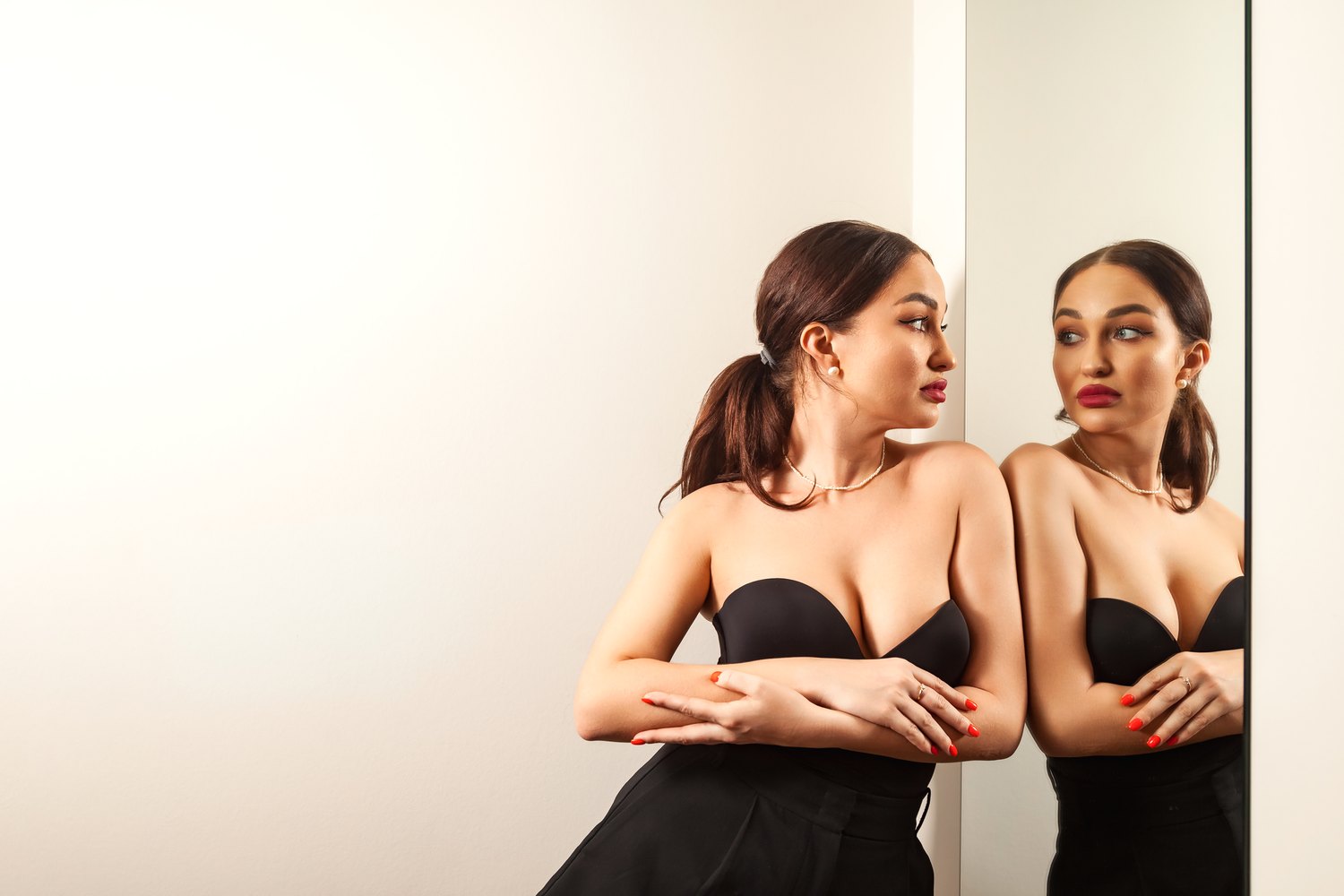 Mujer con un top negro palabra de honor mirándose de perfil en un espejo